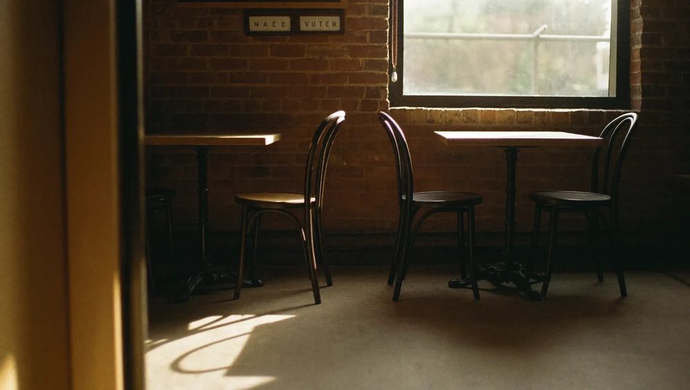 The seating area of the cafe, warm daylight across wooden tables against brick